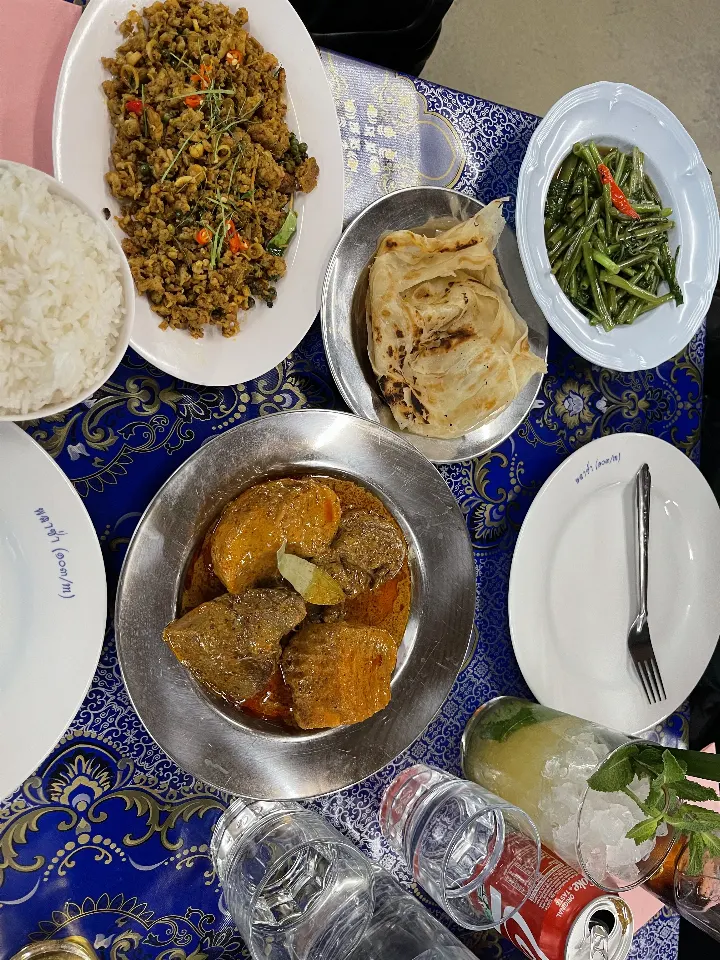 Southern Thai curries, greens and rice on a blue patterned tablecloth.