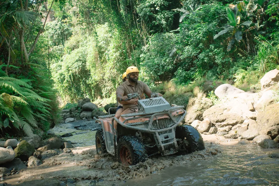 A quad bike splashing through the river on the Beji River adventure.